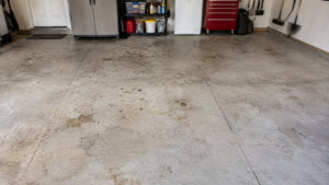 Residential garage floor with natural concrete stains and light wear before a professional floor coating.