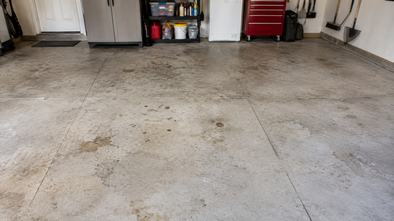 Residential garage floor with natural concrete stains and light wear before a professional floor coating.